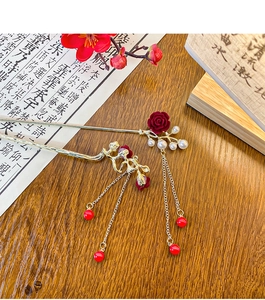 Detail of vintage metal plum blossom hairpins with red tassels and pearls on a wood desk