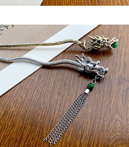 Detailed close-up of gold and silver dragon hairpins with tassels on a wooden desk