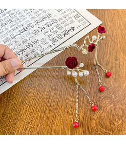 Detail view of two gold Chinese plum blossom hairpins with red tassels and pearls