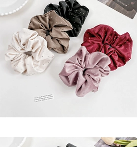 Detailed view of five velvet scrunchies with rhinestones in assorted elegant colors