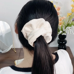 Elegant cream satin scrunchie with sparkling rhinestones worn on a ponytail hair style