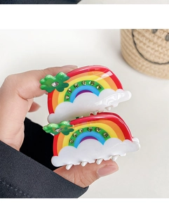 Close-up of rainbow hair claw clips with green rhinestones and clover detail
