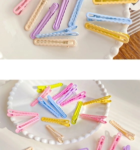Detail of candy-colored wavy metal hair clips in pastel pink, blue and yellow shades