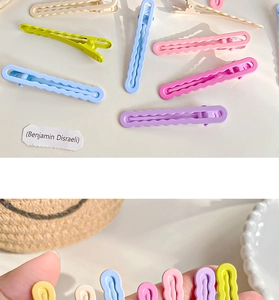 Detailed close-up of wavy macaron-colored duckbill hair clips with a smooth painted finish