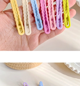 Detail of candy-colored wavy hair clips in macaron shades with smooth metal finish