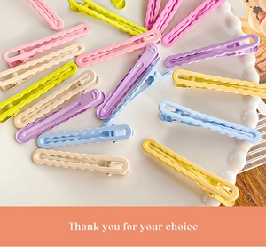 Detailed view of macaron colored wavy duckbill hair clips on a white ceramic tray