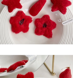 Detail of red plush star and rectangular hair clips on a white plate with cozy styling