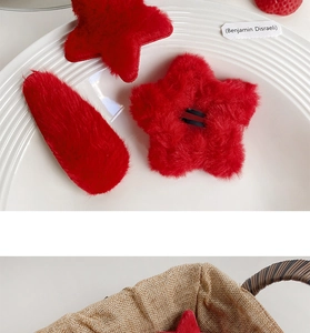 Detailed view of red plush star and teardrop hair clips on a ceramic plate