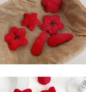 Detailed view of red plush hair clips in star and oval shapes with soft faux fur texture