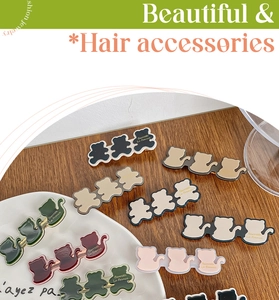 Flat lay of colorful cat and bear hair clips with gold lettering on wooden surface