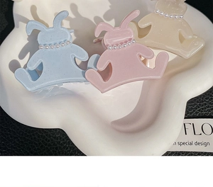 Detailed view of three pastel acetate rabbit hair clips with pearls on a cloud tray