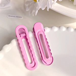 Lot de deux pinces à cheveux rose bonbon géométriques sur une assiette en céramique