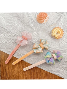 Vue détaillée de trois barrettes à nœud en acétate en rose pastel, orange et bleu-violet