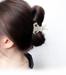 Detail of cream acetate dachshund hair claw clip with pearl accents on a woman's hair