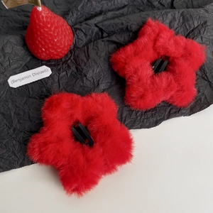 Pair of plush red star hair clips with soft fur texture on a dark textured background