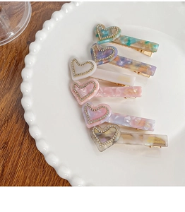 Detailed macro view of heart-shaped acetate hair clips with inlaid rhinestones set in a tray