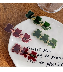 Close-up of four acrylic cat and bear hair clips on a decorative white porcelain plate