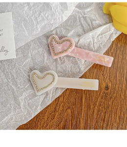 Detail of handmade acetate heart hair clips with rhinestones in pink marble and beige