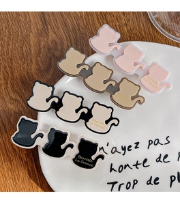 Detailed view of four colorful cat hair clips on a white ceramic plate with wood background