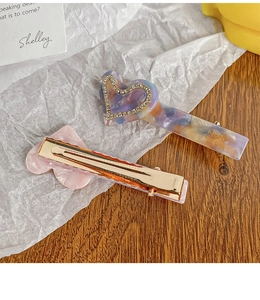 Close-up of acetic acid heart hair clips with marble texture and gold metal alligator grip