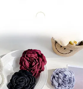 Detailed view of handmade fabric rose hair clips in purple, black, and wine red colors