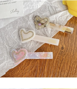 Detailed macro view of heart-shaped acetate hair clips with inlaid rhinestones and gold text