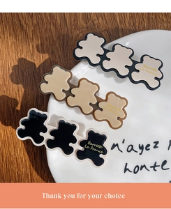Detailed view of three resin bear hair clips with gold lettering on a white ceramic plate