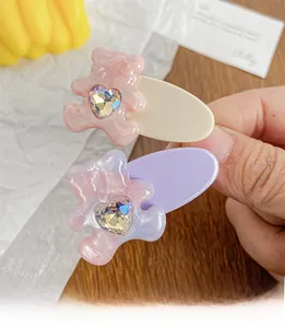 Dettagli di fermagli crema e viola con orsetti in resina e strass a forma di cuore