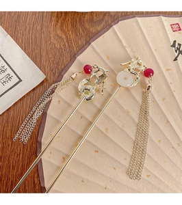 Detailed macro of gold dragon hairpins with jade beads and long tassels on fan