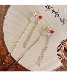 Detail of golden dragon hairpins with jade inlays and tassels on a folding fan