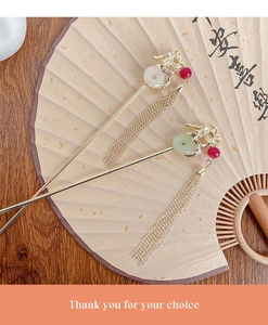 Detailed view of dragon-shaped hairpins with tassels on a traditional folding fan