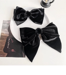 Detailed macro view of black velvet bow hair clips with soft fur ball and metal spring clip