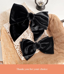 Detail of elegant black velvet bow hair clips with faux fur pom centers in a gift basket