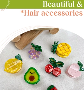 Detail view of colorful resin fruit hair clips including avocado and cherry designs