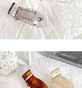 Detail of translucent grey, amber, and cream resin hair claws with strong metal springs