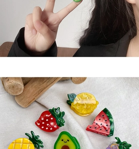 Detailed close-up of colorful fruit-shaped acetate hair claws including strawberry and avocado