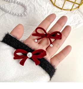 Detailed macro view of two red velvet hair clips with elegant pearl embellishments