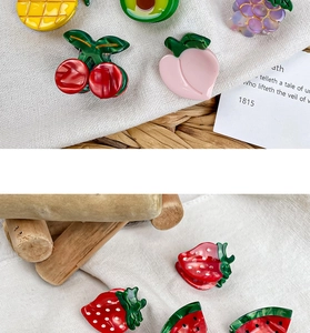 Close-up of mini fruit hair clips featuring strawberry and pineapple designs