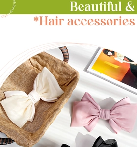 Detail of oversized satin bow hair clips in white and pink with layered pleat design