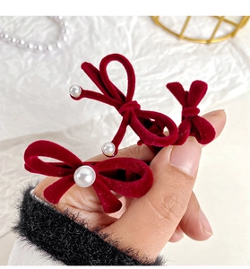 Detail of red velvet bow hair clips with elegant pearl accents and soft fabric texture