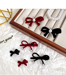 Close-up of velvet bow hair clips with pearls on a vintage wooden jewelry tray