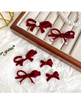 Detail of red velvet bow hair clips with elegant pearl accents on a luxury display
