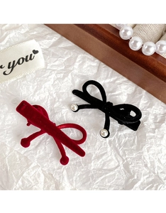 Detailed view of red velvet and black pearl bow hair clips on a wooden box
