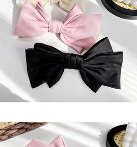 Detail of multi-layered satin bow hair clips in pink and black with soft shadow light