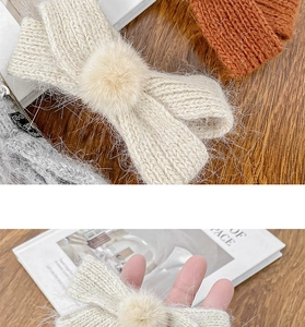 Detail of knitted bow hair clips with soft fur balls in autumn colors on a wooden table
