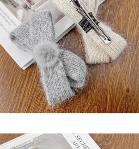 Detail view of winter knitted bow hair clips with plush balls on a wooden surface