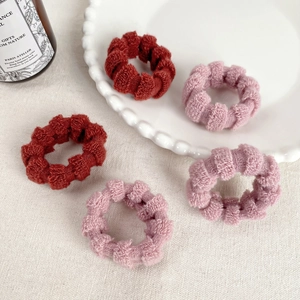 Set di cinque elastici per capelli in peluche rosso ruggine e rosa antico su un piatto