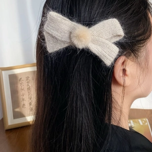 Knitted off-white bow hair clip with plush pom-pom center for autumn and winter styles