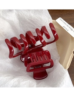 Close-up of deep red glossy resin hair claw clip with durable metal spring on white paper