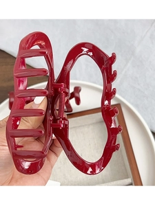 Close-up of a large dark red high-gloss hair claw clip with a strong metal spring